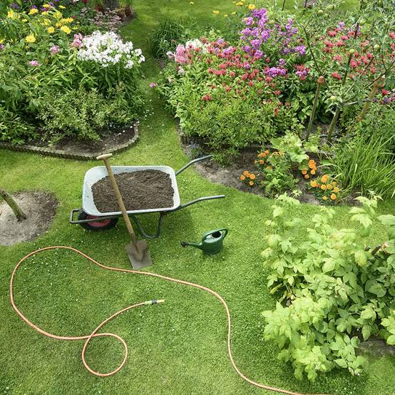 Gärtner schneidet eine gepflegte Hecke vor einer Wohnüberbauung
